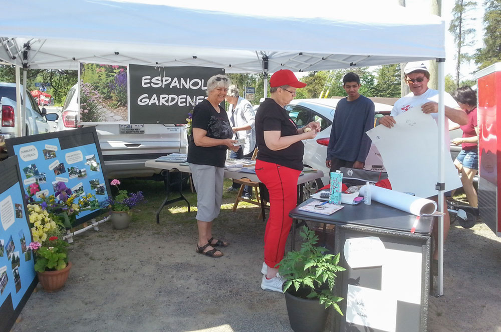 photo of Espanola Gardener volunteers under a tent canopy at a community event