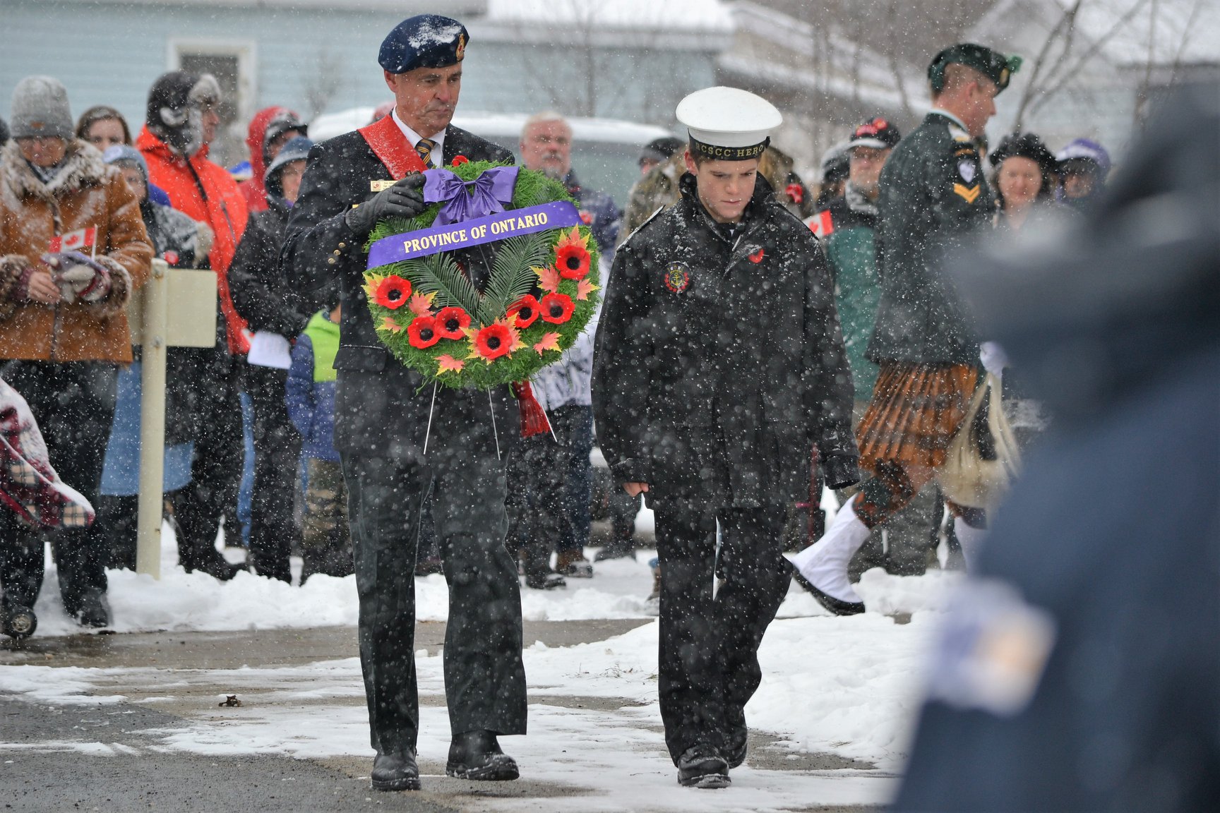 Vets carrying wreath in front of Legion on snow day